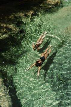 two people are swimming in the clear water