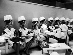 a group of women wearing hard hats sitting next to each other in front of desks