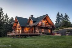 a large log cabin sits on the side of a hill