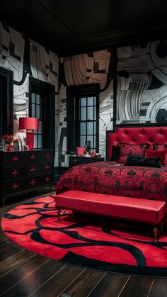 a red bed sitting on top of a wooden floor next to two large black windows