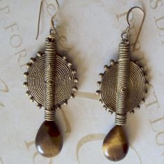 Earrings with large African baule brass accent and tigereye teardrop. Light weight for the materials and length. The baule is 1.5 inches The Tigereye teardrop is .75 inches  The earring from the top of the earwire is 2.75 inches. Bronze Metal Teardrop Earrings, Brown Teardrop Brass Earrings, Bronze Metal Dangle Teardrop Earrings, Bronze Metal Teardrop Dangle Earrings, Adjustable Teardrop Bronze Earrings, Bronze Wire Wrapped Teardrop Earrings, Handmade Bronze Metal Teardrop Earrings, Handmade Bronze Teardrop Metal Earrings, Brass Accents