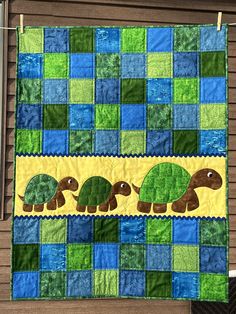 a quilted wall hanging with three turtles on it