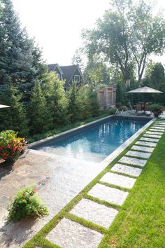 a backyard with a swimming pool surrounded by greenery