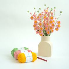 a vase with flowers and yarn next to it