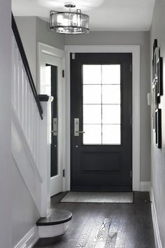 an empty hallway with black door and white trim on the walls, dark wood floors