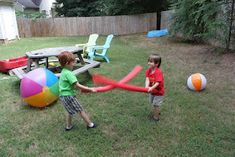 two young boys playing with giant inflatable balls on the backyard lawn at home