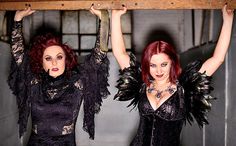 two women dressed in black posing for the camera with wings on their arms and legs