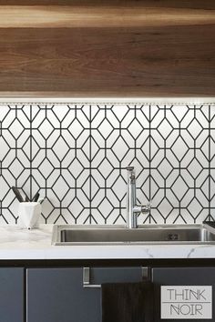 a kitchen counter with a sink, faucet and tiled backsplash above it