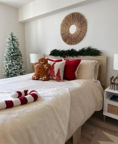 a bedroom decorated for christmas with white bedding and red striped throw pillows on the bed