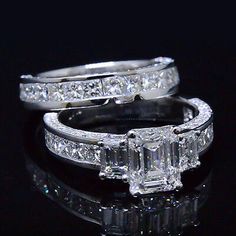 two wedding rings with an emerald cut diamond in the center and side stones on each band