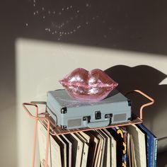 a piece of luggage sitting on top of a stack of records with pink lipstick painted on it