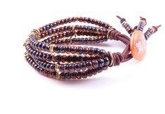 three bracelets with brown beads and an orange bead on the end of each strand