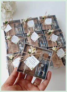 a hand holding a small glass box filled with photos and twine tied around it