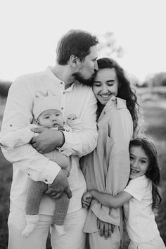 a man, woman and child are posing for a black and white photo with their arms around each other