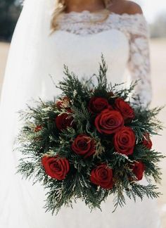 a bride holding a bouquet of red roses