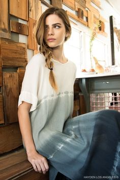 a beautiful young woman sitting on top of a wooden floor next to a table with drawers