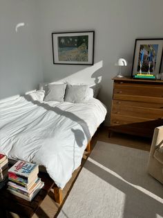 a bed sitting in a bedroom next to a dresser with books on top of it