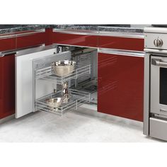 a kitchen with stainless steel appliances and red cabinetry, including pots and pans