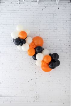 black, white and orange balloons hanging on a brick wall