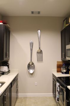 two forks and spoons hanging from the wall in a kitchen