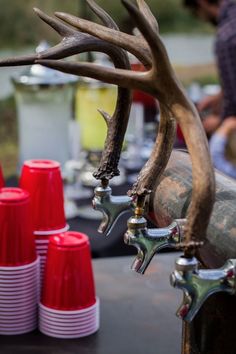 there are several cups and some deer antlers on the table with red cups in front of them