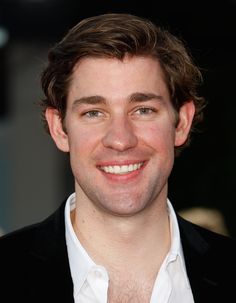 a young man smiling at the camera with white shirt and black blazer over his shoulders