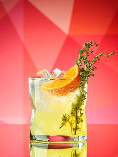 a glass filled with lemonade and garnish on top of a red table