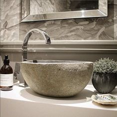 a bowl shaped sink sitting on top of a counter next to a bottle of wine