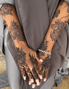 two hands with henna tattoos on them, one is holding the other's hand