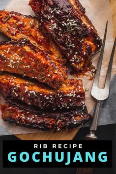 ribs covered in sauce and garnished with herbs on a cutting board next to a knife