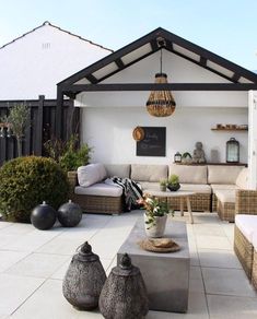 an outdoor living area with couches, tables and potted plants on the patio