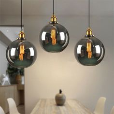 three glass globe lights hanging over a dining room table