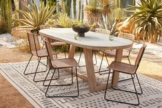 a wooden table with four chairs and a potted plant in the middle of it