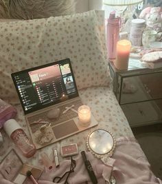 an open laptop computer sitting on top of a bed next to candles and other items