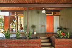 a house with brick steps leading to the front door and potted plants on either side