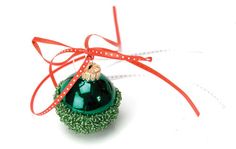 a green ornament with a red ribbon tied around it on a white surface