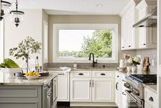 a kitchen filled with lots of white cabinets and counter top space next to a window