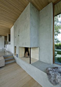 the interior of a modern house with wood floors and walls, including a fireplace in the center