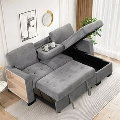 a grey couch with two pillows and a coffee table in the middle is open to reveal a storage compartment