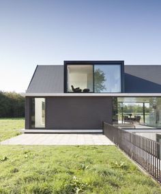 a modern house in the middle of a grassy area with a fence and grass lawn