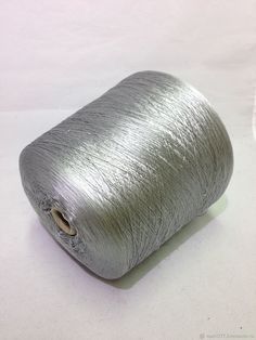 a spool of silver colored thread on a white surface