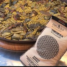 a large bowl filled with food sitting on top of a table next to a bag of rice