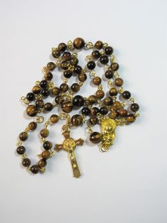 "This Tiger's eye Catholic rosary is made with Grade a gemstones. The hand turned links are gold plated as is the connector. The golden cross is from Italy. The rosary measures 26\" in the body and has a 5\" cross drop. This rosary will be slipped into a velvet bag and shipped in a bubble mailer." Gold Rosary With Gemstone Beads Gift, Gold Rosary Bracelet With Cross And 8mm Beads, Gold Spiritual Rosary With Gemstone Beads, Gold Spiritual Rosary Bracelet With Polished Beads, Gold Rosary Bracelet With Natural Stones And Round Beads, Gold Gemstone Beads Rosary, Spiritual Gold Rosary With 8mm Beads, Gold Spiritual Rosary With Cross, Gold Spiritual Rosary With Round Beads