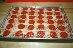 a pizza sitting on top of a metal pan covered in cheese and pepperoni slices