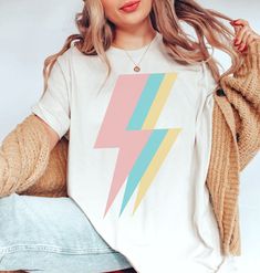 "This Lightning Bolt Shirt makes a cute Y2K Top. Gift to a VSCO Girl or Preppy Clothes For Teens Wear as a beachy tee or oversized tee.  Bella Canvas. SIZING.  Adult unisex sizing, which is MENS SIZING. For the oversized look order 1-2 sizes up.  Be sure to check out the sizing guide in the images to ensure you order the correct size, as there are no refunds allowed since all items are made to order.  Lay your favorite shirt at home flat and measure armpit to armpit to compare to the size chart Teen Graphic Tees, Graphic Tee Oversized, Shirts Y2k, Clothes For Teens, Preppy Clothes, Vsco Girl, Y2k Top, Aesthetic Clothing, Trendy Shirts