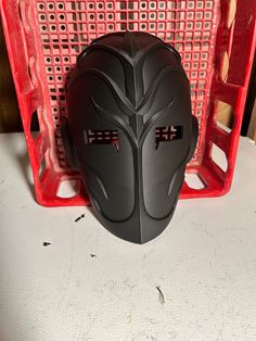 a motorcycle helmet sitting on top of a red basket next to it's side