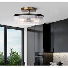 a kitchen with black cabinets and a round glass chandelier hanging from the ceiling