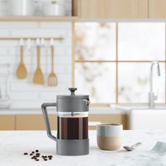 a coffee maker sitting on top of a kitchen counter next to a cup and spoon