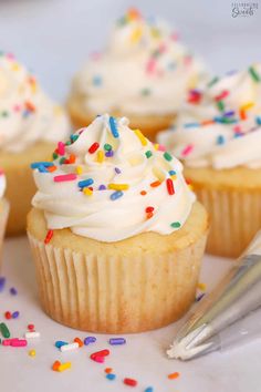 several cupcakes with white frosting and sprinkles