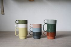 four different colored coffee mugs sitting next to each other on a wooden counter top